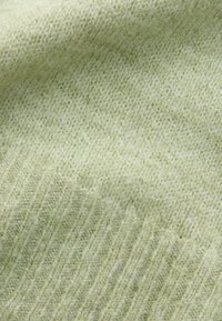 Lichtgroene gebreide stof met een zachte textuur; heeft een diagonale ribstructuur en subtiele schaduwvariaties. Ideaal voor kleding of accessoires.