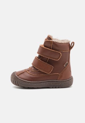 Stivale a caviglia in pelle marrone con tre fasce Velcro, foderato in pelliccia sintetica, suola in gomma e punta rinforzata per una maggiore durata.