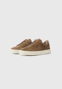 Baskets slip-on en suède marron avec une surface texturée, dotées d'une semelle en caoutchouc et de détails de couture subtils, conçues pour un usage décontracté.