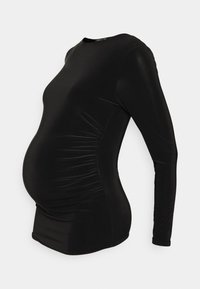Camisa preta de manga longa feita de um material elástico, com laterais franzidas para um ajuste mais justo, projetada para acomodar uma silhueta grávida.