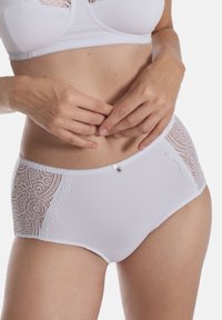 Weiße Unterwäsche mit Spitzenpaneelen an den Seiten, die eine glatte Oberfläche, dekorative Spitzenverzierungen und ein kleines, metallisches Herzdetail auf der Vorderseite aufweist.