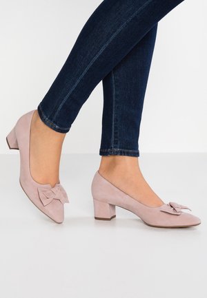 Chaussures à talon bloc en suède rose pâle avec un nœud décoratif sur le bout. Design à bout rond avec une finition texturée et un talon ferme.