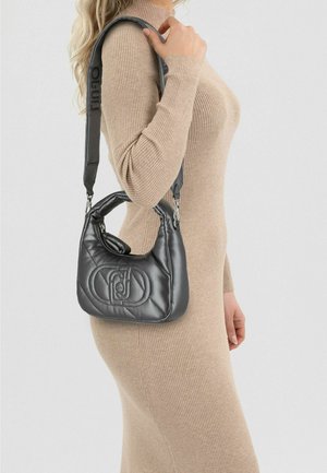 Gewatteerde zwarte leren handtas met afgeronde bovenkant, verstelbare schouderriem en logodetail. Heeft een gladde textuur en ritssluiting.