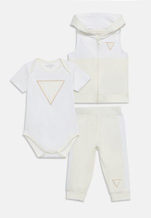 Ensemble de vêtements pour bébé trois pièces comprenant un body blanc à manches courtes, un sweat à capuche sans manches zippé et un pantalon aux poignets avec des logos triangulaires beiges.
