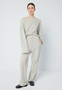 Ensemble de vêtements de détente gris en tissu doux, comprenant un haut à épaules dénudées avec des manches longues et un pantalon large assorti avec une taille élastique.