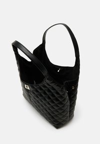 Czarna pikowana torba na ramię z gładką teksturą skóry, z podwójnymi uchwytami oraz wewnętrzną kieszenią na zamek. Z metalowym logo na boku.