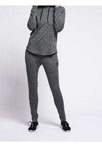 Conjunto de ropa deportiva gris que incluye una sudadera con capucha y un pantalón ajustado a juego. Ambos artículos tienen una textura jaspeada y detalles de logotipo.