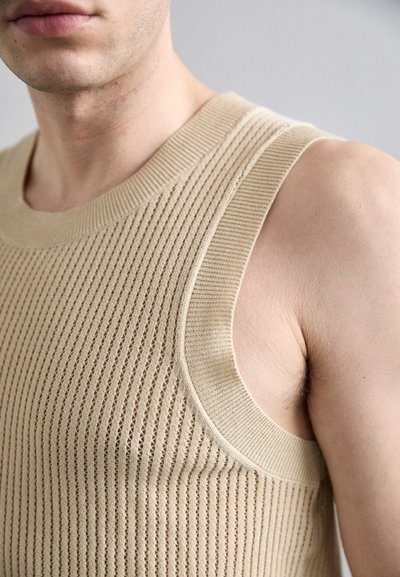 Top de tanque sin mangas en color beige, con textura de punto acanalado y rayas horizontales, que presenta un escote de cuello redondo y una silueta ajustada.