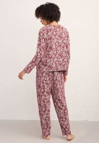 Ropa de casa con estampado floral en burdeos y crema, que presenta mangas largas y pantalones holgados. Fabricado en un tejido suave y transpirable.