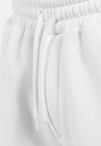 Weiße Baumwoll-Jogginghose mit strukturierter Oberfläche, ausgestattet mit einem gerippten Bund und Kordelzügen. Das Design beinhaltet seitliche Taschen.