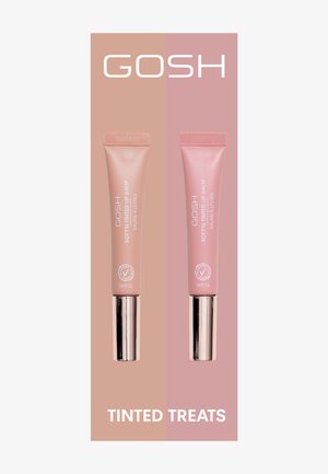 Deux tubes de baume à lèvres teinté GOSH Soft’n, un rose pâle et un rose doux, avec des accents argentés, sur un fond bicolore. Indication de SPF 15.