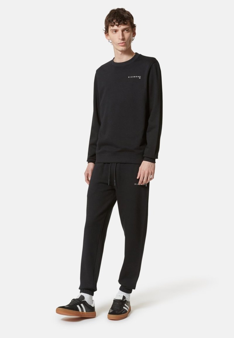 Felpa nera e pantaloni della tuta in misto cotone, con polsini elasticizzati, colletto tondo e dettagli con logo sul petto e sulla gamba.