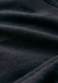Textil negru cu o textură fină, nervată. Suprafață netedă și strălucire subtilă, cu straturi de țesătură pliate care formează valuri blânde.
