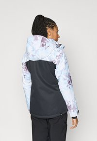 Ūdensizturīga jaka ar ziedu rakstu maigi zilā un purpursarkanā krāsā, ar melnu apakšdaļu un regulējamu kapuci. Teksturēts audums dažādās toņu nokrāsās.