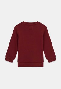 Sweatshirt bordeaux à manches longues, poignets côtelés et col rond. Le tissu semble doux et texturé avec un ourlet droit en bas.