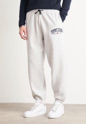 Grå sweatpants med elastisk talje og manchetter, prydet med mørkeblå "TOMMY JEANS NEW YORK CITY" tekst på venstre lår.