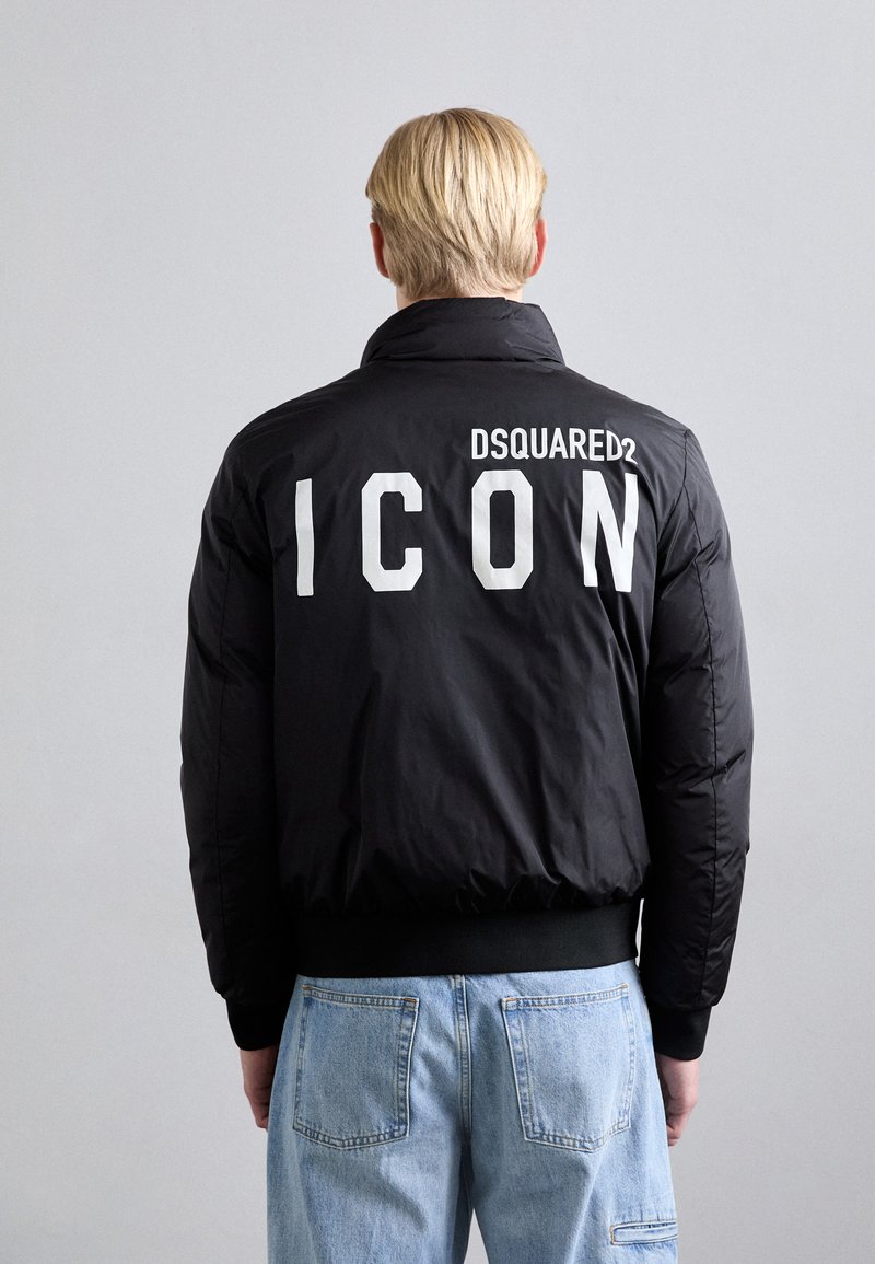 Black puffer jacket with a high collar, featuring white "ICON" text and "DSQUARED2" logo on the back. Ribbed cuffs and waistband.