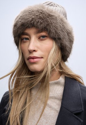 Bonnet tricoté avec un large bord en fourrure grise douce. Présente un corps gris clair avec un motif texturé, offrant chaleur et confort.