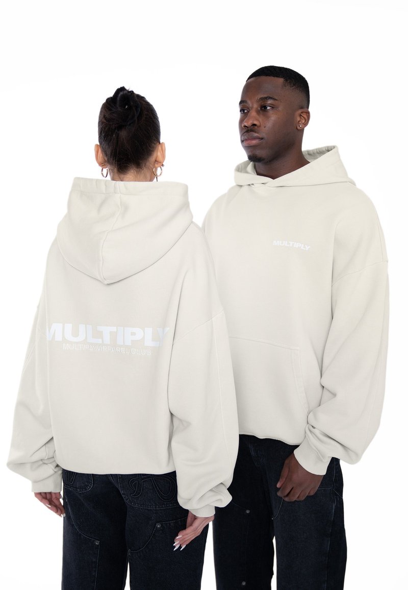 Prekryté krémové mikiny s nadmernou veľkosťou a jemnou textúrou. Obsahujú predné vrecko, biely logom "MULTIPLY" na chrbte a rebrované manžety.