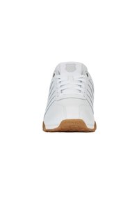 Bílé sportovní boty s koženým svrškem, světle šedými pruhy a gumovou podrážkou, s tkaničkami a vystouplým logem na jazyku.