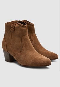 Brown suede ankle boots with a ruffled top edge, pointed toe, and 2-inch wooden heel. Smooth texture and classic design.