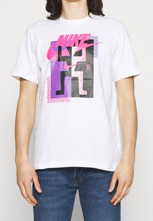 Biała bawełniana koszulka z dużym nadrukiem graficznym w różowo-fioletowych elementach, w tym tekstem i geometrycznymi kształtami. Standardowy okrągły dekolt.
