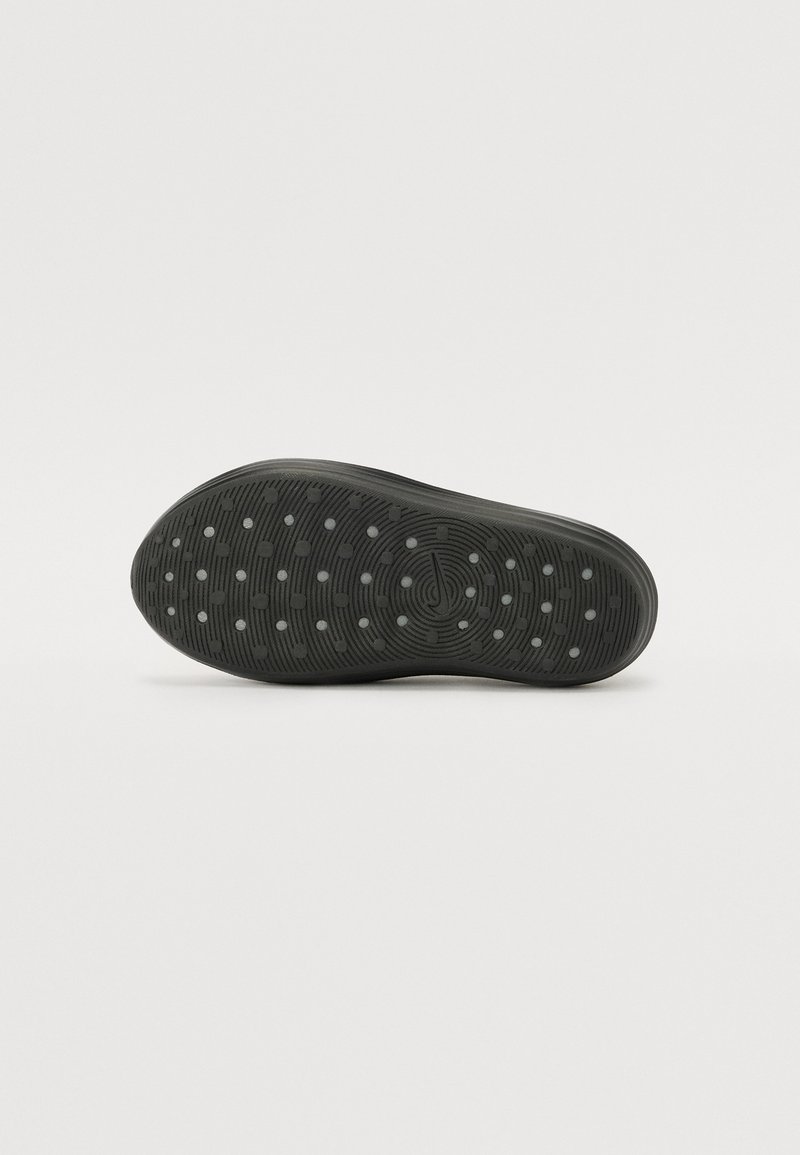 Semelle de chaussure en caoutchouc noir avec un motif circulaire et à pois pour l'adhérence, dotée d'un bord lisse et arrondi à la pointe et au talon.