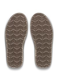Une paire de semelles de chaussures avec des motifs de bande de roulement en zigzag en caoutchouc marron, vues par le dessous sur un fond blanc.