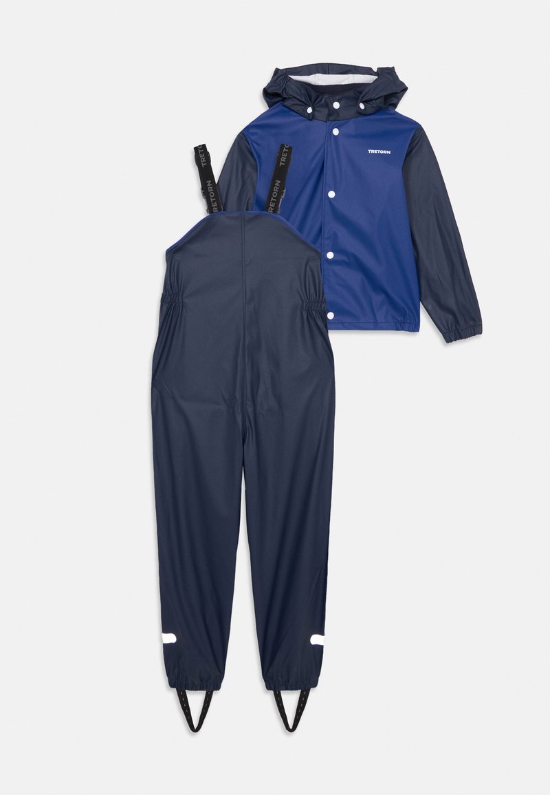 To-delt regntøysett inkluderer en blå jakke med hette og et marineblått overall. Vanntett materiale, elastisk midje, reflekterende detaljer ved mansjettene.