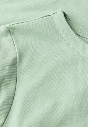 T-shirt en coton vert clair avec une texture côtelée, présentant un col arrondi et des manches courtes. Des détails de couture soignés sont visibles.