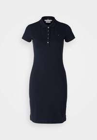 Navy polo dress made of cotton blend, featuring a collar, short sleeves, button placket, and fitted silhouette with subtle side slits.