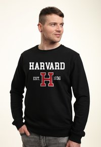 Felpa nera con grafica "HARVARD EST. 1636" in bianco e rosso. Collo rotondo, polsini e orlo a coste. Tessuto morbido, vestibilità casual.