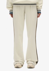 Witte uitlopende sweatpants met zijkanten in bruin en zwart, gemaakt van zacht materiaal, met een relaxte pasvorm en subtiele textuur.