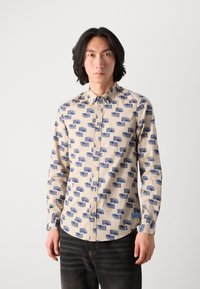 Langærmet skjorte i beige med marineblå geometrisk print. Har en knaplukning foran og en buet kant. Stofstrukturen ser glat og let ud.