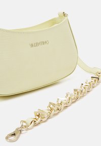 Yellow textured leather handbag with a curved shape, featuring a gold chain strap and embossed 'Valentino' logo on the front.