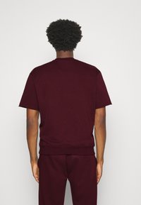 Sudadera de pullover burdeos con mangas cortas. Tejido de mezcla de algodón suave, cuello redondo acanalado y dobladillo. Diseño minimalista sin gráficos.