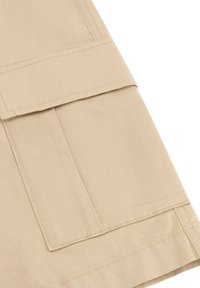 Pantaloni cargo beige con patta e tasche laterali. Realizzati in tessuto leggero con cuciture visibili e design a vita piatta.