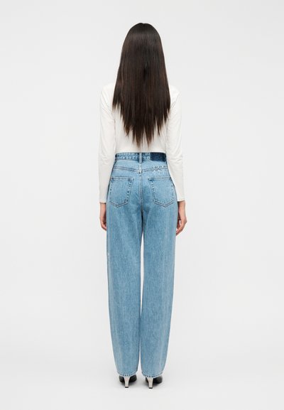 Ανοιχτό μπλε τζιν με ψηλή μέση και φαρδιά γραμμή, διακοσμημένα με δύο πίσω τσέπες και ελαφρώς ξεθωριασμένη υφή.