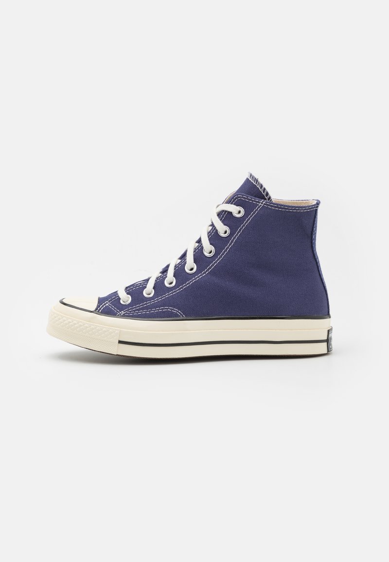 Høj-til-kort sneakers lavet af blå canvas med hvide snørebånd, gummitåhætte, cremet sål og sort kantlinje. Simple stikninger.