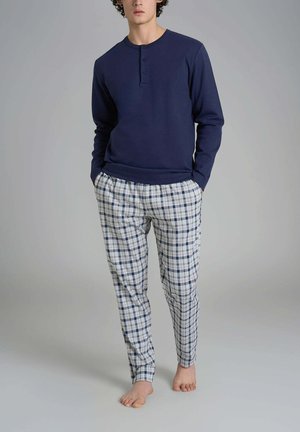 Maglia a maniche lunghe blu navy con collo a giro e tre bottoni, abbinata a pantaloni a quadri bianchi, blu navy e azzurri.