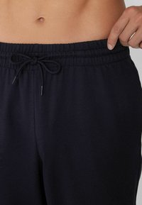 Joggers de algodón en color azul marino con cinturilla elástica y cordón, textura suave y bolsillos laterales. Diseño simple y casual.