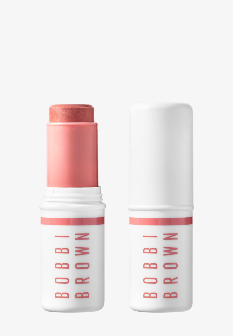 Rosa kremblush-stift med hvit hette, en åpen og en lukket, begge merket med "Bobbi Brown" i rosa bokstaver på hvit bakgrunn.