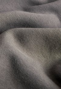 Tessuto grigio con una superficie liscia, caratterizzato da una vista ravvicinata che evidenzia la trama e le sottili variazioni di tonalità.