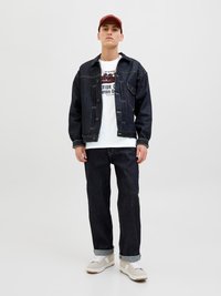 Tume denimi jakk, millel on suured taskud, valge graafiline T-särk, tumedad teksad rullitud sääreotsadega ja beežid tossud valgete aktsentide ja nööbiga.