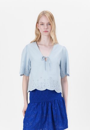 Lichtblauw t-shirt met korte mouwen, V-hals, strikdetail aan de voorkant en scalloped zoom met oogjes uitsnijpatronen.