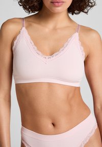 Lichtroze geribbelde bralette met kantafwerking langs de v-hals en schouderbanden, met een zachte textuur en rekbare stof voor comfort.