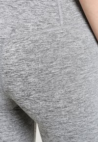 Szare legginsy sportowe z teksturowanym, melanżowym materiałem. Konstrukcja ma dopasowany krój i bezszwowy pasek w talii.