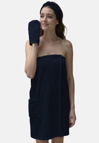 Accappatoio blu navy realizzato in materiale morbido, dotato di una tasca laterale e di un cerchietto coordinato. Include anche un guanto abbinato.