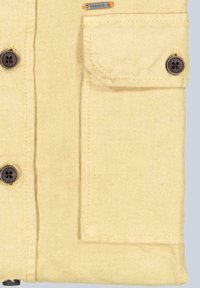 Beige Hemd mit braunen Knöpfen, Taschen und gestickten Details. Aus strukturiertem Stoff gefertigt. Verfügt über eine Klapptasche und einen Metalllabel-Akzent.