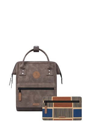 Brauner wasserdichter Rucksack mit einem oberen Griff, einer vorderen Reißverschlusstasche und rundem Logo. Begleitet von einer gemusterten Geldbörse in Blau, Orange und Creme.